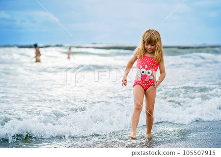 Happy Child, Little Preschool Girl in Swimmsuit Running And Jumping In The Waves During Summer Vacation On Exotic Tropical Beach. Family Journey On Ocean Coast. 105507915
