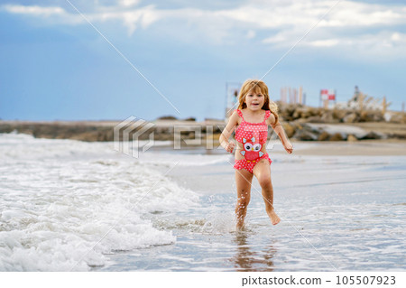 Happy Child, Little Preschool Girl in Swimmsuit Running And Jumping In The Waves During Summer Vacation On Exotic Tropical Beach. Family Journey On Ocean Coast. Happy Child, Little Preschool Girl in Swimmsuit Running And Jumping In The Waves During Summer Vacation On Exotic Tropical Beach. Family Journey On Ocean Coast. 105507923