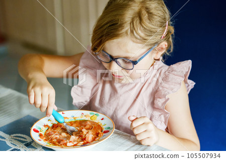 Little preschool girl eating from spoon vegetable potato soup. Healthy food for children. Happy kid at home or nursery. Little preschool girl eating from spoon vegetable potato soup. Healthy food for children. Happy kid at home or nursery. 105507934