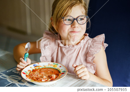 Little preschool girl eating from spoon vegetable potato soup. Healthy food for children. Happy kid at home or nursery. Little preschool girl eating from spoon vegetable potato soup. Healthy food for children. Happy kid at home or nursery. 105507935