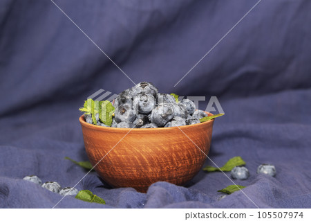 Fresh blueberries in an orange ceramic bowl with mint leaves 105507974