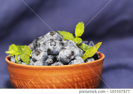 Fresh blueberries in an orange ceramic bowl with mint leaves Fresh blueberries in an orange ceramic bowl with mint leaves 105507977