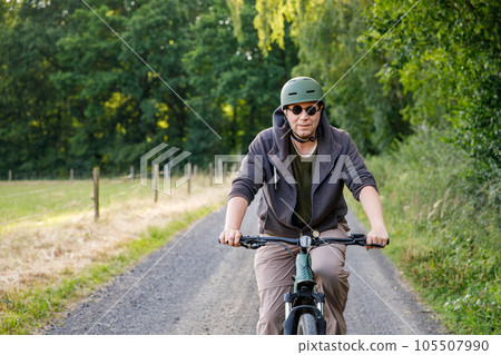 Mountain biker riding on bike in summer forest landscape. Active middle-aged man cycling on bicycle, sports and leisure activity. 105507990