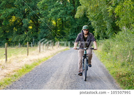 Mountain biker riding on bike in summer forest landscape. Active middle-aged man cycling on bicycle, sports and leisure activity. 105507991