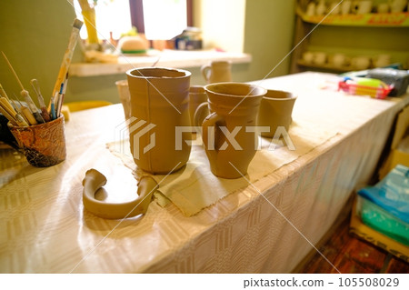Overhead view of hand arranging completed pottery wares. Potter's workplace, tools. 105508029