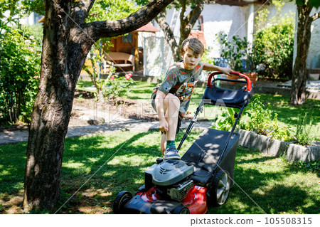 Happy preteen kid boy with lawn mower. Portrait of smiling teenager child working in garden, trimming grass. Garden works in summer. Kid helping Happy preteen kid boy with lawn mower. Portrait of smiling teenager child working in garden, trimming grass. Garden works in summer. Kid helping 105508315