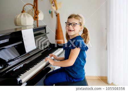 Beautiful little preschool girl playing piano at music school. Cute child having fun with learning to play music instrument. Early musical education for children 105508356