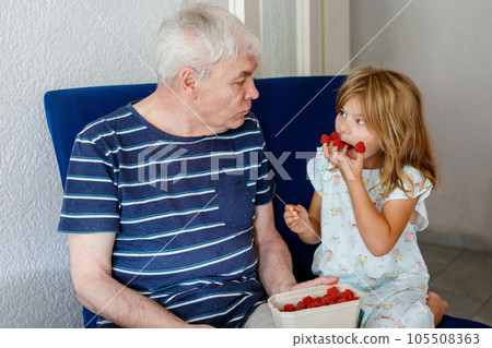 Grandpa And Granddaughter Eating Raspberries At Home. Happy Preschool Girl And Senior Man Having Fun Together. Child And Grandfather, Family Time. 105508363
