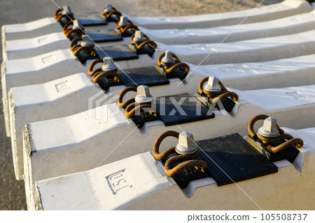 Before track repair stacked new white reinforced concrete railroad track sleepers with rail mounts 105508737
