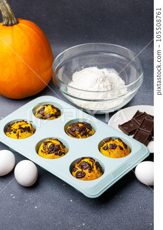Pumpkin muffins baked in the silicone mold at the table with ingredients. 105508761