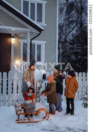 Children stack gifts in a sleigh in the yard of the ranch-style house Children stack gifts in a sleigh in the yard of the ranch-style house 105509011