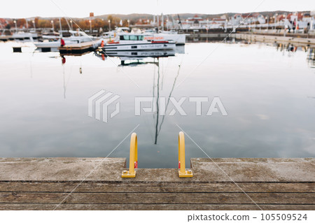 Old wooden pier with ladders. Many yachts and boats are moored at the pier. Boating and rest on the yacht. Vacation at sea. Selective focus. 105509524