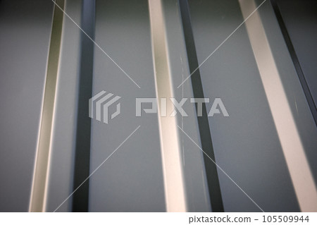 Gray corrugated metal cladding on industrial building roof 105509944