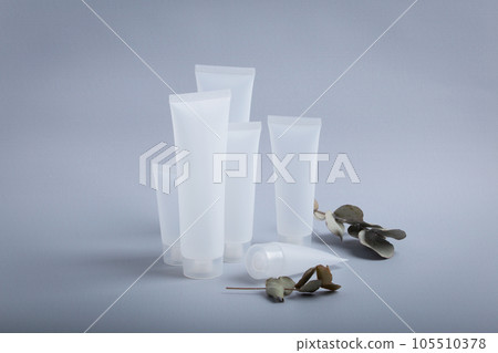 White empty plastic cosmetic tubes staying at gray background with eucalyptus branches, concept of cosmetology, body and skincare, beauty industry White empty plastic cosmetic tubes staying at gray background with eucalyptus branches, concept of cosmetology, body and skincare, beauty industry 105510378