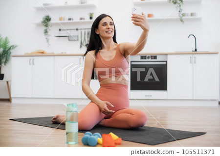 Lady making selfie on smartphone while training on yoga mat 105511371