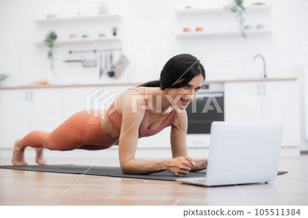 Fitness woman doing plank and listening to music indoors Fitness woman doing plank and listening to music indoors 105511384