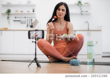 Fitness coach sitting on mat and telling about organic meal Fitness coach sitting on mat and telling about organic meal 105511390