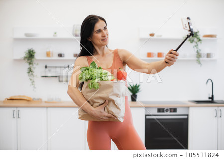 Woman in sportswear taking selfie with fresh food at home 105511824