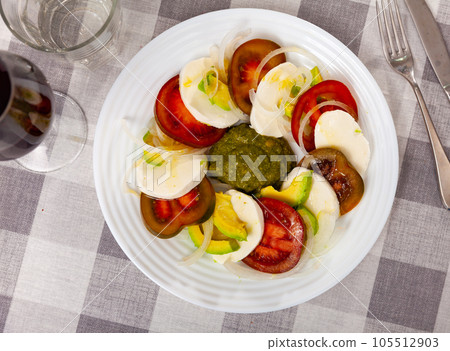 Salad with tomatoes, mozzarella, onion, avocado with pesto Salad with tomatoes, mozzarella, onion, avocado with pesto 105512903