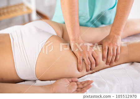 Anti cellulite thigh massage in the salon close-up. Masseur doing leg massage to woman 105512970