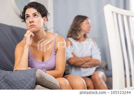 Two young adult women ignoring each other after home quarrel Two young adult women ignoring each other after home quarrel 105513244