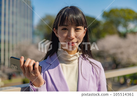 A woman holding a smartphone in her right hand 105514361