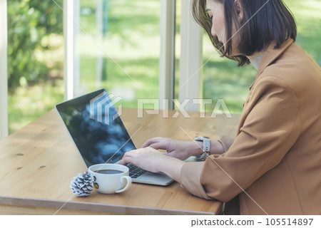 Close up Woman Hands love drinking hot coffee working from home. Business women with black coffee or hot chocolate cafe. Businesswoman hand typing laptop drink black coffee cup in green garden cafe 105514897