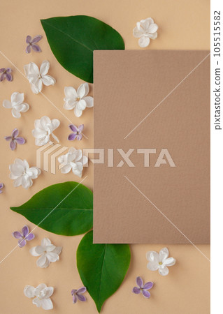 Composition with empty envelope and beautiful spring lilac flowers on beige background. Mockup card invitation greeting card postcard copy space template. Branches of lilac blooming bouquet.  105515582