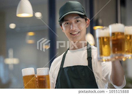 一名年輕人拿著啤酒杯餐廳大廳工作人員的照片 105515888