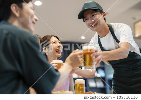 大廳工作人員將啤酒杯遞給餐桌上的顧客​ 105516116