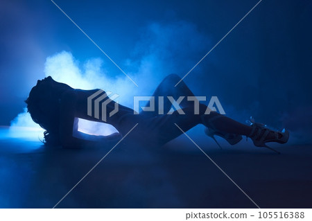 Slim naked woman laying in studio with neon light and smoke Slim naked woman laying in studio with neon light and smoke 105516388
