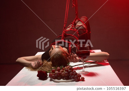 Alluring woman lying on the dinner table during BDSM game 105516397