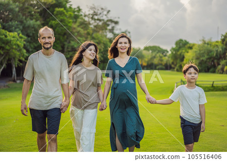 A loving family enjoying a leisurely walk in the park - a radiant pregnant woman after 40, embraced by her husband, and accompanied by their adult teenage children, savoring precious moments together A loving family enjoying a leisurely walk in the park - a radiant pregnant woman after 40, embraced by her husband, and accompanied by their adult teenage children, savoring precious moments together 105516406