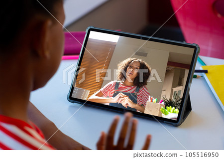 Rear view of a african american boy having a video call with female teacher on a tablet at home Rear view of a african american boy having a video call with female teacher on a tablet at home 105516950