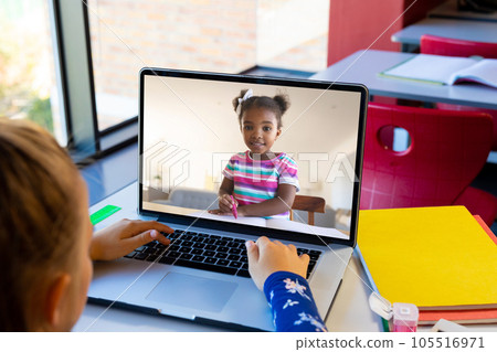 Caucasian girl using laptop while having a video call with african american girl at school Caucasian girl using laptop while having a video call with african american girl at school 105516971
