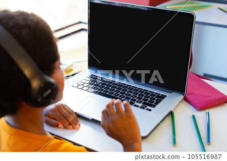 Rear view of a biracial boy wearing headphones having a video call on laptop with copy space at home Rear view of a biracial boy wearing headphones having a video call on laptop with copy space at home 105516987