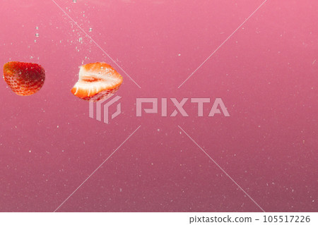 Close up of strawberries falling into water with copy space on pink background Close up of strawberries falling into water with copy space on pink background 105517226