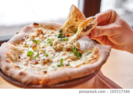 one people takes slices of pizza. Neapolitan pizza from a wood-fired oven. Pizza is on the plate. Pizza with pear and gorgonzola. Fast delivery of food. one people takes slices of pizza. Neapolitan pizza from a wood-fired oven. Pizza is on the plate. Pizza with pear and gorgonzola. Fast delivery of food. 105517380