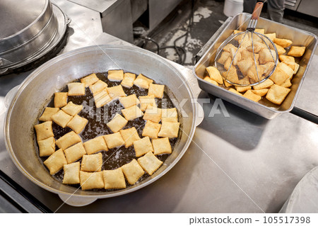 Male cook preparing delicious National Kazakh pastries baursak. street cafe. Fry dough in boiling oil in a frying pan. Male cook preparing delicious National Kazakh pastries baursak. street cafe. Fry dough in boiling oil in a frying pan. 105517398