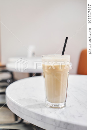 Glass of cold cappuccino with ice. The table in the coworking space of the coffee shop. A cup of coffee on the veranda on a sunny day. Coffee break at the cafe. Close-up 105517467