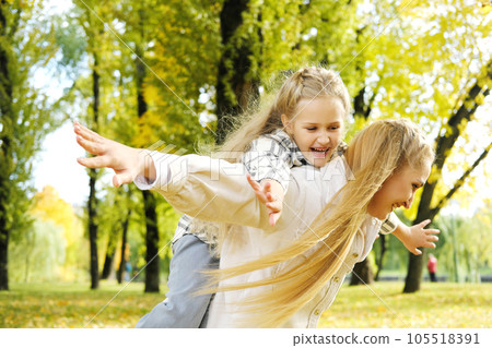 Play, flying or mother with girl on back in autumn park bonding, quality time and playing outdoors. Love, airplane and happy mom piggyback with child on weekend 105518391