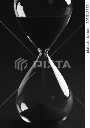 Close up of hourglass with black sand and copy space on black background 105518583
