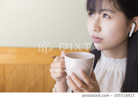 戴著無線耳機，在一家咖啡館喝咖啡的年輕女子 105518915