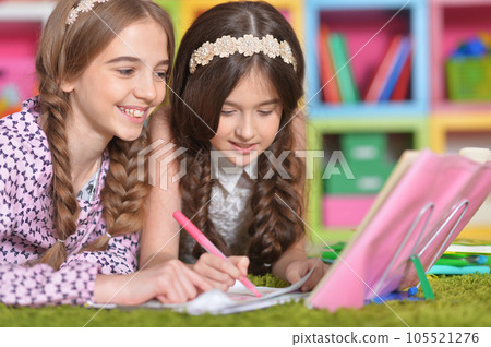 Two school age kids doing their homework on floor at home. Brother and sister siblings children drawing together, preparing for school lesson. Homeschool concept. 105521276