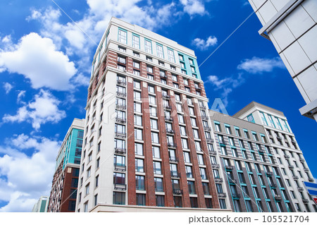 new brick building, red, white, grey, blue modern apartment building on blue cloudy sky, residential complex. view from below from street. 105521704
