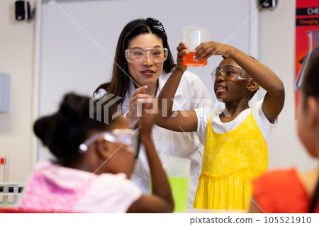 Diverse female teacher and schoolgirls with chemistry items and liquids in elementary school class Diverse female teacher and schoolgirls with chemistry items and liquids in elementary school class 105521910