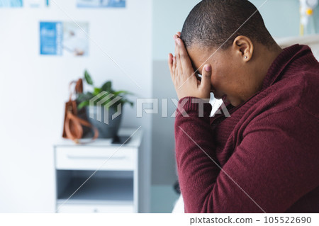 Sad african american female patient sitting on bed and crying in patient room at hospita, copy space Sad african american female patient sitting on bed and crying in patient room at hospita, copy space 105522690