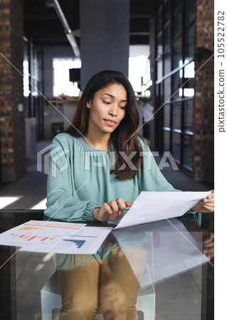 Busy biracial casual businesswoman having video call with documents in office 105522782