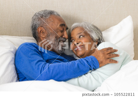 Happy senior biracial couple lying in bed and embracing at home Happy senior biracial couple lying in bed and embracing at home 105522811