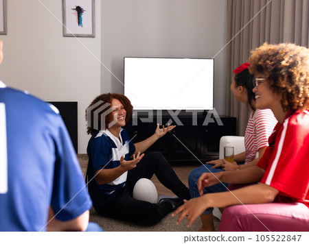 Happy group of diverse friends with rugby ball talking and watching tv with copy space at home Happy group of diverse friends with rugby ball talking and watching tv with copy space at home 105522847